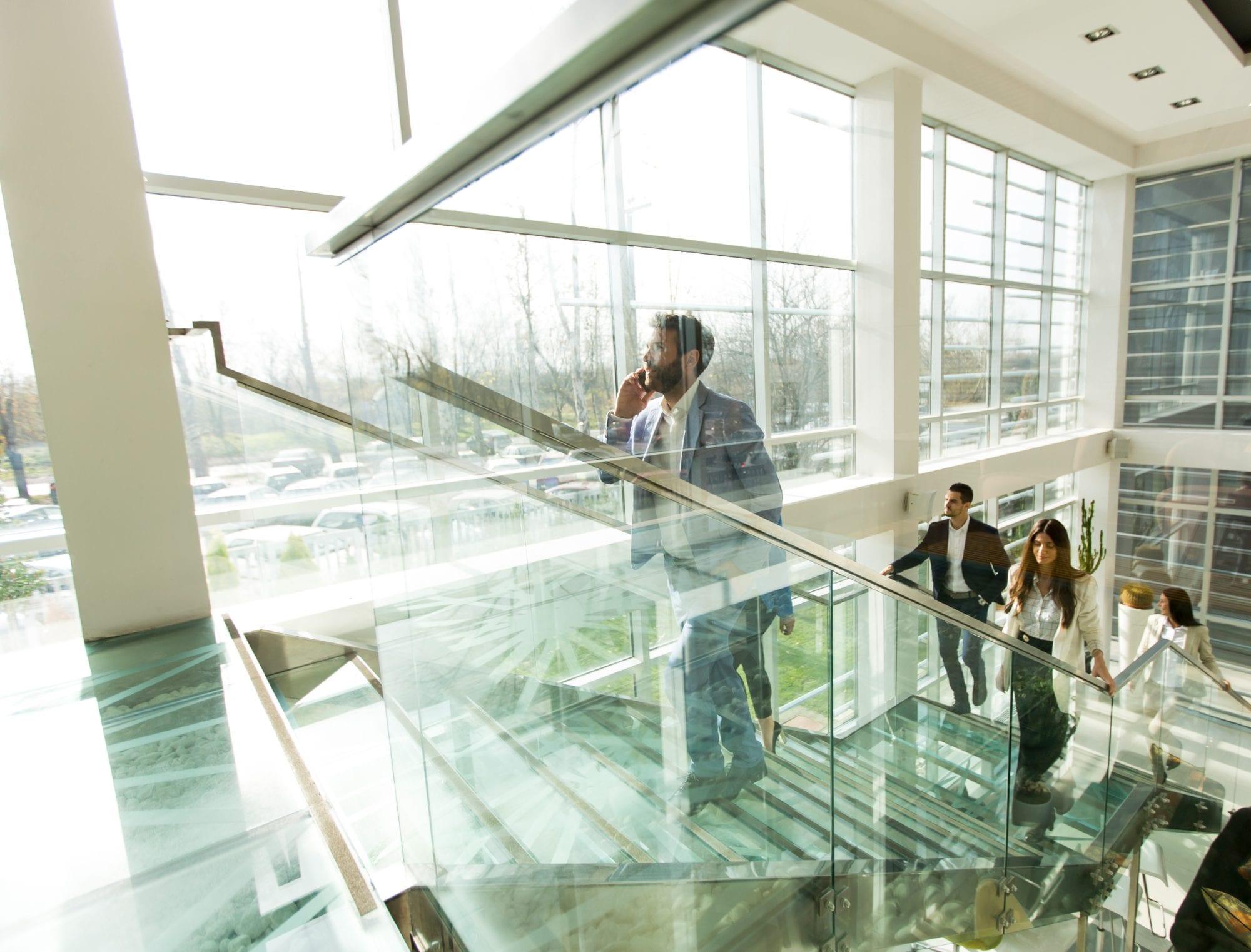 Colleagues walking down a glass staircase in a bright office