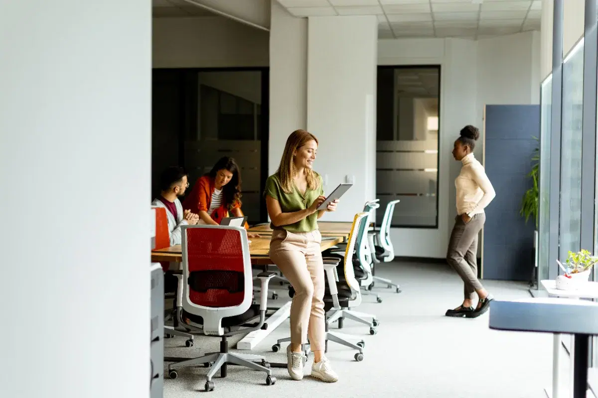Colleagues working around a table in a bright open-plan office, one holding a tablet