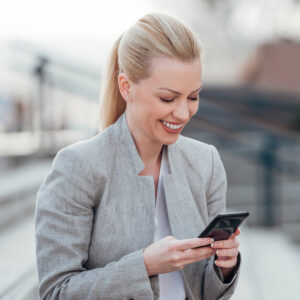 Female smiling down at her cellphone while using Teams Phone.