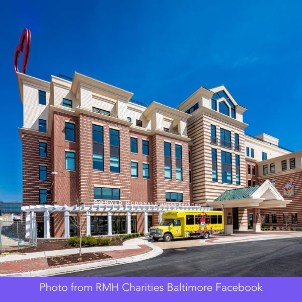 A modern brick building with multiple stories and large windows under a clear blue sky. A yellow school bus is parked in front, creating a welcoming, friendly atmosphere.
