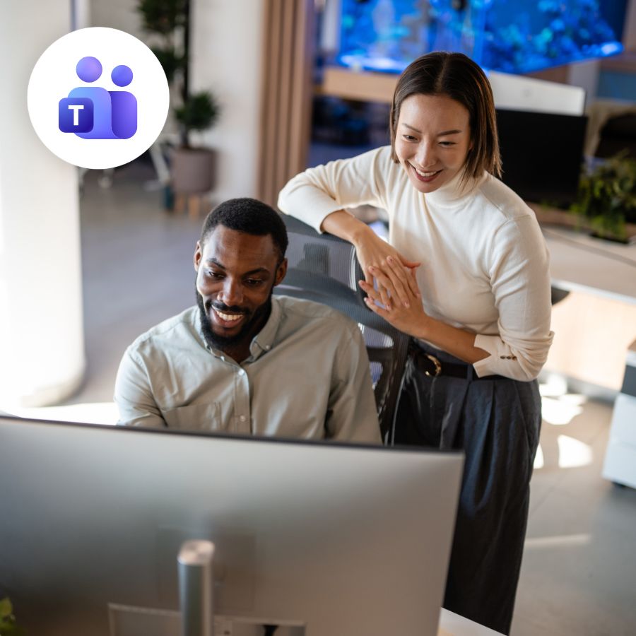 A man and woman cheerfully collaborate at a computer in a modern office. The Microsoft Teams logo is displayed. Bright, professional atmosphere.