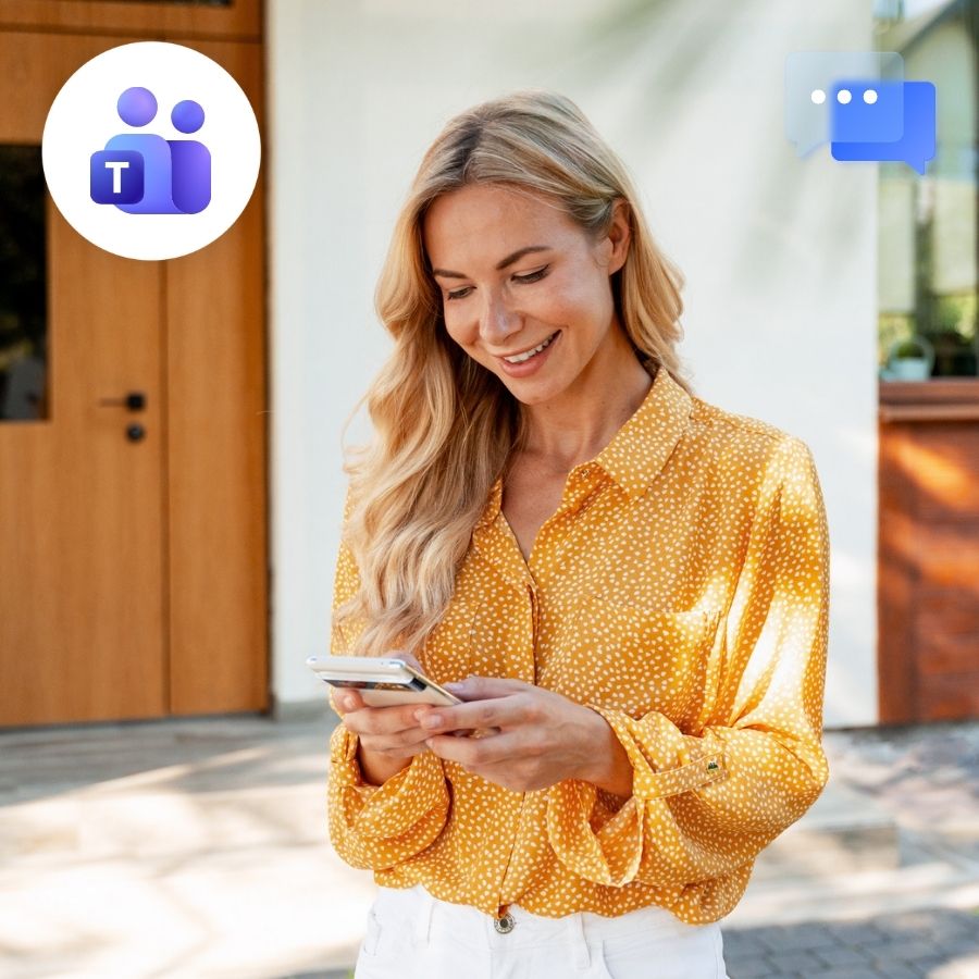 Woman in a yellow blouse smiling at her phone outside a home entrance, Teams and chat icons.