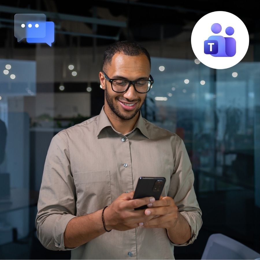 Man in a tan shirt texting on a smartphone in a modern glass-walled office, Teams and chat icons.